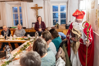 Ein als Bischof Nikolaus verkleideter Mann in einem Saal mit Menschen