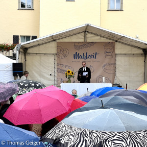 Pfarrer Björn Schukat bei seiner Predigt (mit Regenschirmen)