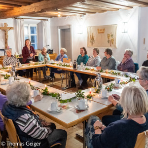 Menschen sitzen um eine weihnachtlich dekorierte Tafel